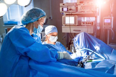 Teknolojik olarak gelişmiş bir ameliyathaneyi ameliyat yapan insanlarla görüntülemek. Çalışma ekipmanları, ışıklar ve bilgisayarlarla ameliyathane.