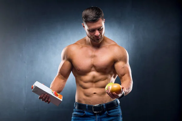 健美运动员拿着水果和果汁 选择纯的还是浓缩的饮料 灰色背景 — 图库照片
