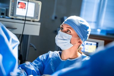 Ameliyat sırasında cerrahi maske takan profesyonel hemşire asistanının portresi. Modern hastane ameliyathanesi.