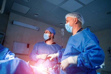 Tıbbi ekip, parlak modern cerrahi odasında cerrahi operasyon gerçekleştiriyor. Ameliyathane. Klinikte modern ekipmanlar. Acil Servis..