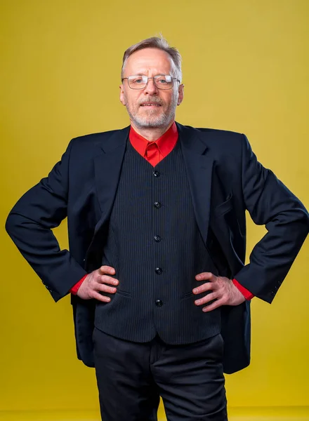 Portrait of middle age man in suit and eyesglasses isolated on yellow background