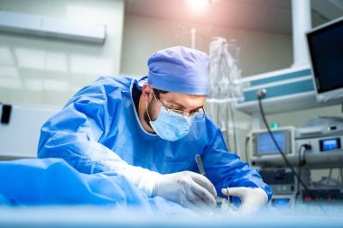 Tıp, ameliyat ve insan konsepti. Ameliyat odasında koruyucu maskesi olan bir erkek doktor ya da cerrah. Kapat.