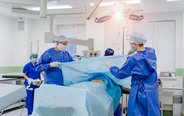 In surgery. Medical team performing operation in hospital operating theater. Working with surgical instruments.