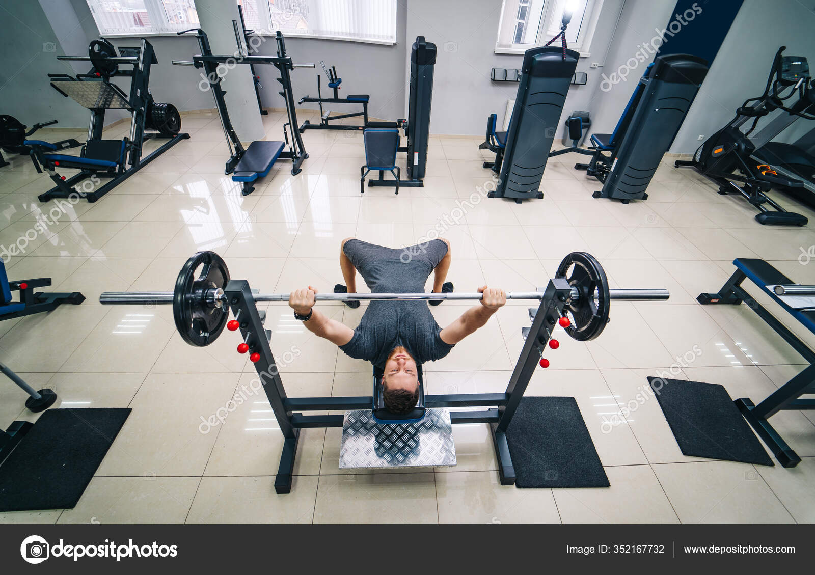 Bodybuilder trainer man doing bench press workout in gym. Photo from