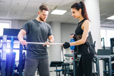 Spor salonunda antrenörle antrenman yapan formda bir kadın. Sporcu ve güzellik antrenman yapıyor. Sağlık hayatı spor konsepti.
