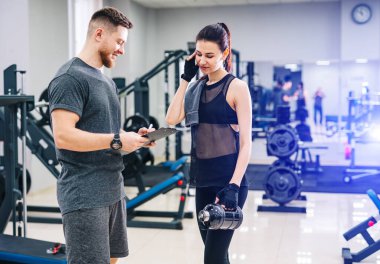 Spor salonunda kişisel antrenörüyle birlikte genç ve güzel bir kadın adamın tuttuğu bir panoda ilerlemesini tartışıyor. Sağlıklı yaşam tarzı
