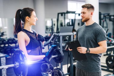 Kişisel yakışıklı fitness eğitmeni ve spor programında çalışan güzel bayan müşteri. Sağlıklı yaşam konsepti.