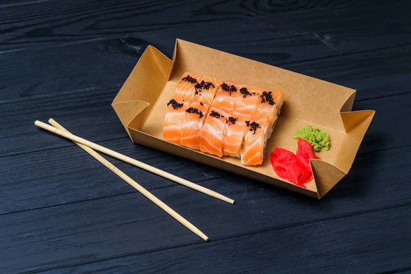 フィラデルフィア寿司は箸でロールします 黒の背景 フードデリバリーサービス — ストック写真