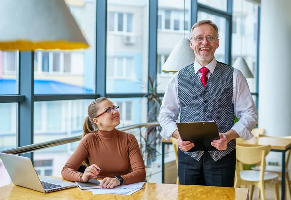 Senior businessman discussing business ideas with the assistance. Mature man and businesswoman in an office. Photo from the business lunch