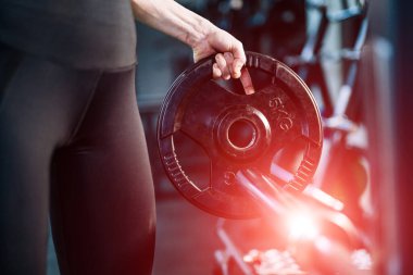 Güzel vücutlu bir kadın spor salonunda poz veriyor. Siyah tişörtlü, tozlu kız bar için gözleme tutuyor..