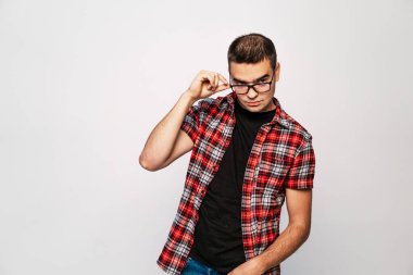 Beyaz stüdyo yakın çekim gözlük gülümseyen genç trendy biri vurdu. Yeni gözlük kameradan bakarak ve bunları test t-shirt zeki adam portresi.