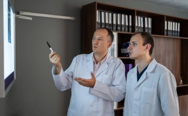 Röntgen filmlerine bakan iki cerrah hastanede hasta hastalığına teşhis koyuyor. Tıbbi konsept. Tıbbi konular tartışılıyor..