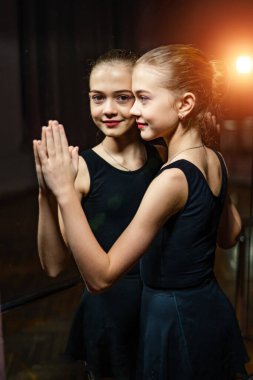 Aynaya dokunan küçük çekici balerin portresi. Aynadaki genç balerin ve refleksi. Siyah beyaz fotoğraf.