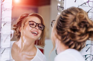Güzel kız gözlükçü mağazasında gözlüklü. Görme düzeltme. Optik. Duygular. Göz hastalıkları.