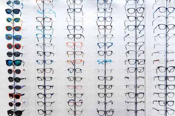 Sunglasses and glasses in the shop display shelves. Stand with glasses in the store of optics.