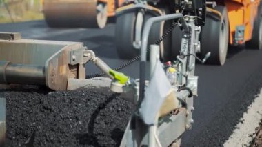 Profesyonel ekipman zifti karıştırıyor ve karışımı yoldan geçen bir paten makinesinin arka planına koyuyor.