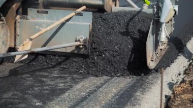 Profesyonel ekipmanlar ziftle dolduruluyor ve asfalt paketlemek için yolda düzleştiriliyor. Modern yol onarım teknolojisi