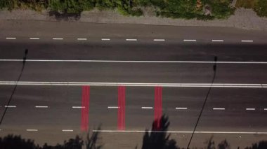 Yoldan kırmızı işaretli ve yaya geçidi olan arabalar geçiyor. Hava görüntüsü. Kameranın sağa hareketi