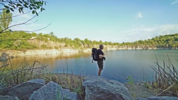 Turysta Plecakiem Ramionach Patrzy Kolorowy Teren Nad Rzeką Spaceruje Skale — Wideo stockowe
