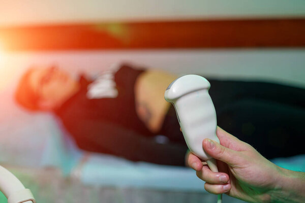 Сонограф проводит ультразвуковое исследование в клинике, крупным планом
