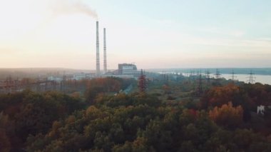 Nehir ve ağaçların arka planında elektrik hatları olan elektrik santralinin manzarası. Hava görünümü