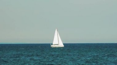 Yazın beyaz yelkenli, sahilden çok uzakta denizde yüzüyor. Yavaş çekim