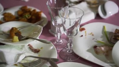 Bulaşık kırıntıları, tatilden sonra restoranda pembe arka planda beyaz tabaklarda. Arta kalanlar.