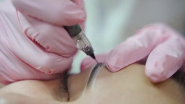 Usta, profesyonel iğneyle kalıcı kaş makyajı yapıyor. Kaşlar şekil düzeltmesi. Kozmetoloji