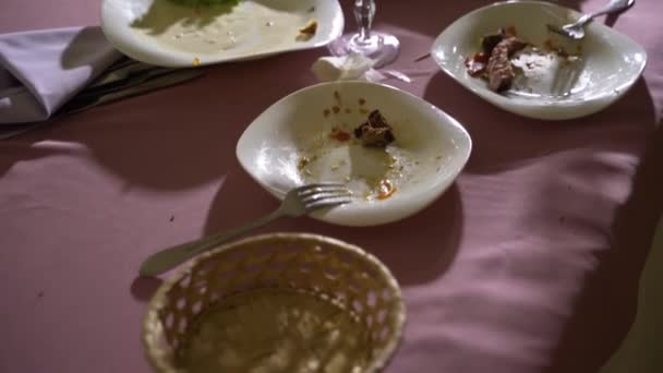 ワイングラスのついた汚れた皿や刃物はピンクのテーブルクロスに置かれています 前方カメラの動き — ストック動画