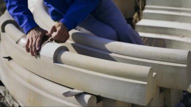 Usta, tahta kolonları zımpara kağıdıyla parlatıyor ve plağı fırçayla ovuyor. Ahşap. Mobilya
