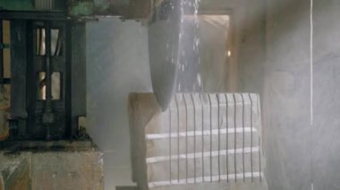 Profesyonel bir makine, bir taş işleme tesisinin inşaatında büyük bir taş kesiyor. Su kullanarak taş işleme teknolojisi