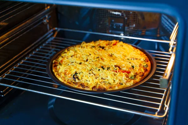 Pizza with cheese on a round tray in an oven. Horizontal view.