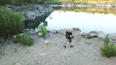 Bir turistin havadan görünüşü gölün kayalık kıyısı boyunca yürür. Uçurumdaki gezgin. Kamp sezonu