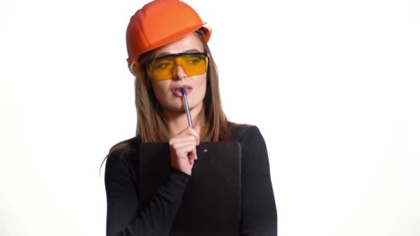 年轻的女建筑工人戴着白色背景的硬礼帽 有魅力的女建筑工人手里拿着记事本做决定 — 图库视频影像