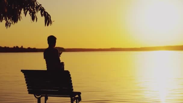 Little Boy Sitting Bench Playing Paper Boat Background Evening Landscape — Stock Video