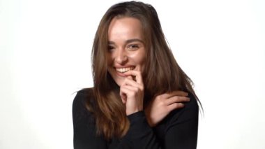 Çekici model gülümsüyor ve stüdyoda beyaz bir arka planda poz veriyor. Yakın plan.
