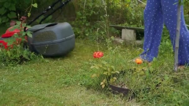 庭に草を刈る 裸足の少女芝刈り機と芝生の芝刈り機で庭 — ストック動画