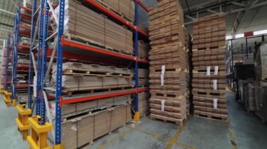 Yüksek metal mavi renkli raflar ahşap bir fabrikanın deposunun ahşap tahtalarıyla doludur. İçeriden büyük parke depolama görüntüsü