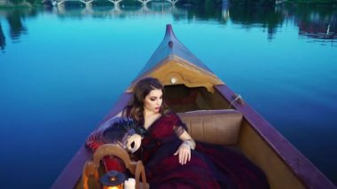 Kırmızı elbiseli çekici bir kadın akşam gondola biniyor. Venedik 'teki karnaval. Mavi arkaplan