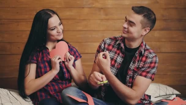 Счастливая Влюбленная Пара Режет Бумажные Сердечки Красного Картона Кровати Фоне — стоковое видео