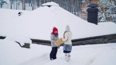 Küçük bir oğlan ve kız binadan çok uzak olmayan zarftaki görüntüye baktılar ve kış ormanı yakınlarındaki patika boyunca ilerliyorlar..