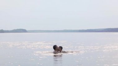 Mutlu bir aile. Baba ve oğul eğleniyor ve suya su sıçratıyorlar. Yavaş çekim.