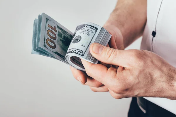 Businessman holds money in hands. Male counts income. Money is stacked in dollar bills.