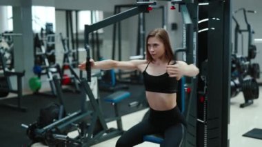 Dalgalı saçlı güzel bir kadın spor salonunda göğsü için egzersiz yapıyor. Profesyonel ekipmanlar. Sağlıklı yaşam tarzı