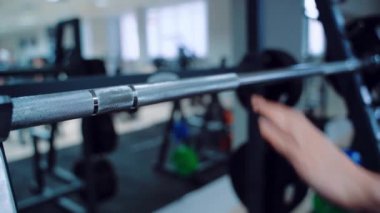 Bir kadın ellerini aynanın karşısındaki salonda halterin üzerine koyar. Güç egzersizleri yapmaya hazırlanıyorum. Bulanık Arkaplan