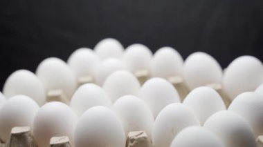 El yumurtaları bir kutuya koyar. Yumurtalar tepsiye istiflenmiş..