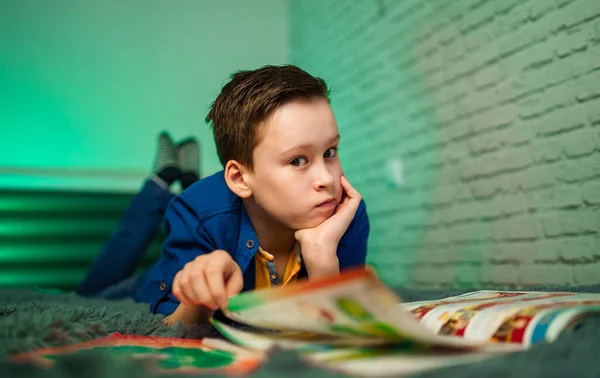 少年は家で読書本を読んで寝そべっている 家庭教育 — ストック写真