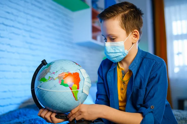 Earth globe in face mask in boy hands. Air and environment pollution. Save the planet concept.