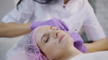 Güzel bir kadın kozmetolojide kozmetik uzmanı ile bir kanepede uzanıyor. Yakın plan.