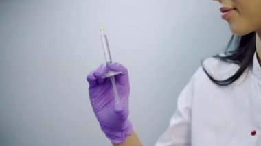 Mor eldivenli bir güzellik uzmanı elinde tıbbi kozmetoloji merkezinde bir botulinyum toksini tutuyor. Yakın plan. Prosedüre hazırlanma